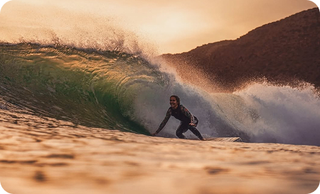 surf house desert point - a girl surfing at sunset